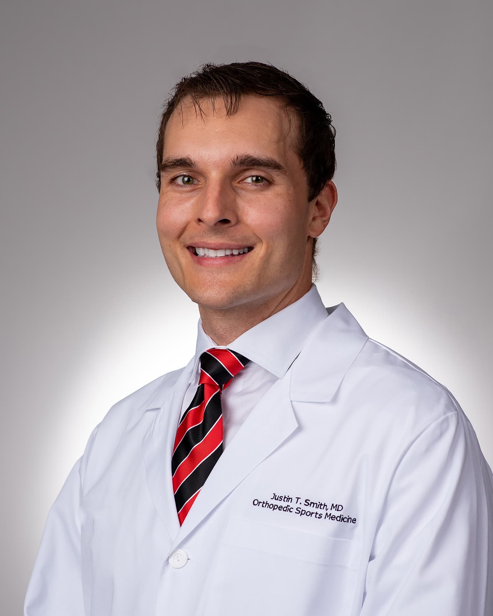 Dr. Justin T. Smith, MD, orthopaedic sports surgeon, in his white coat